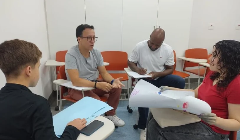 Lenilson Gabriel conversando com jovens em uma sala de aula durante atividade voluntária